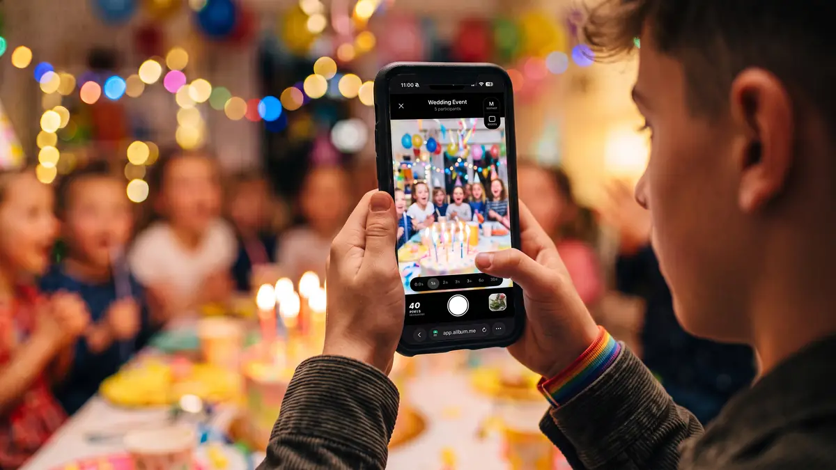 Young guest photographing a birthday party with a smartphone
